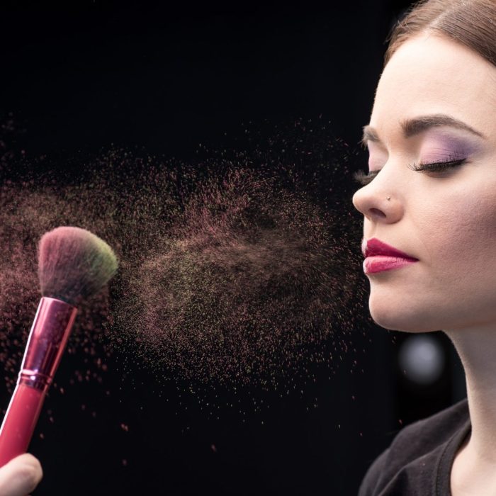 make-up-artist-sprinkling-model-s-face-with-powder-with-help-of-brush-on-black.jpg